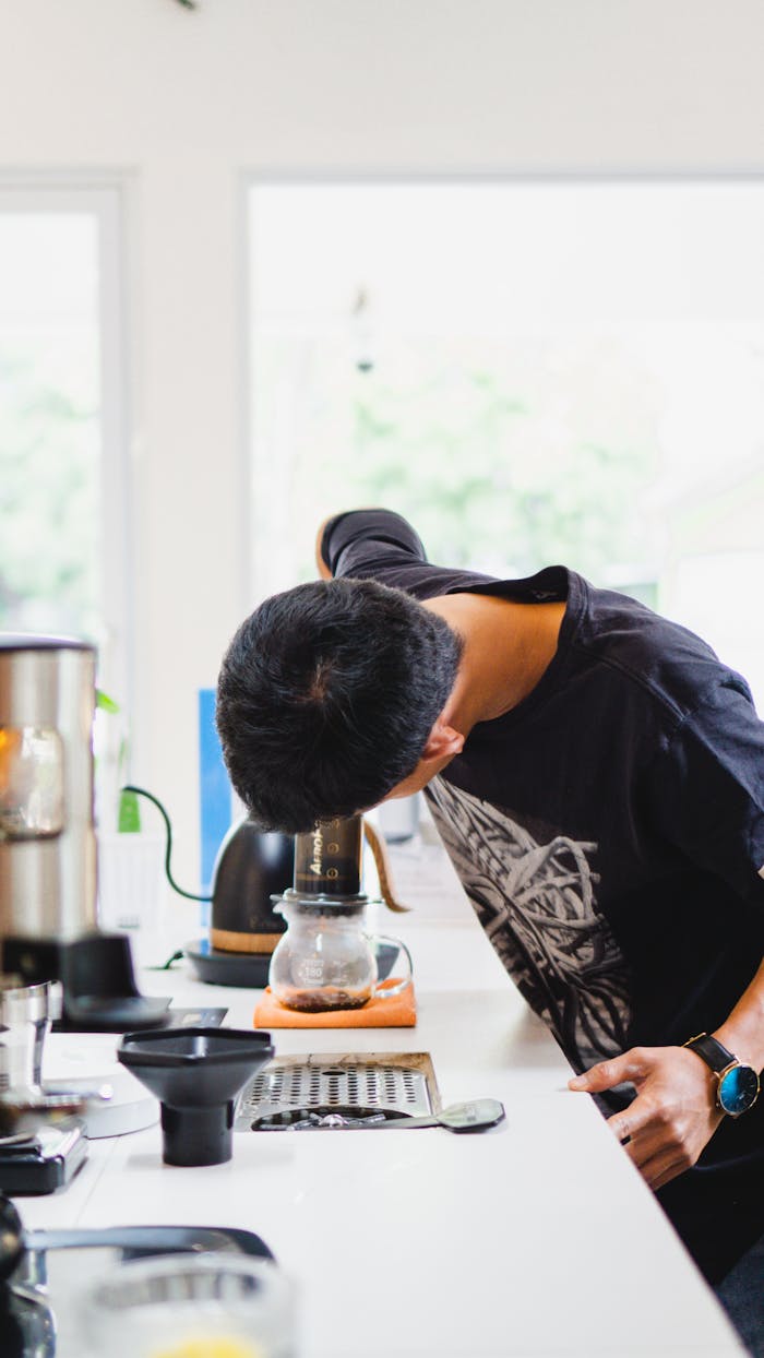 A barista brewing coffee using an Aeropress in a modern cafe in Madiun, Indonesia.